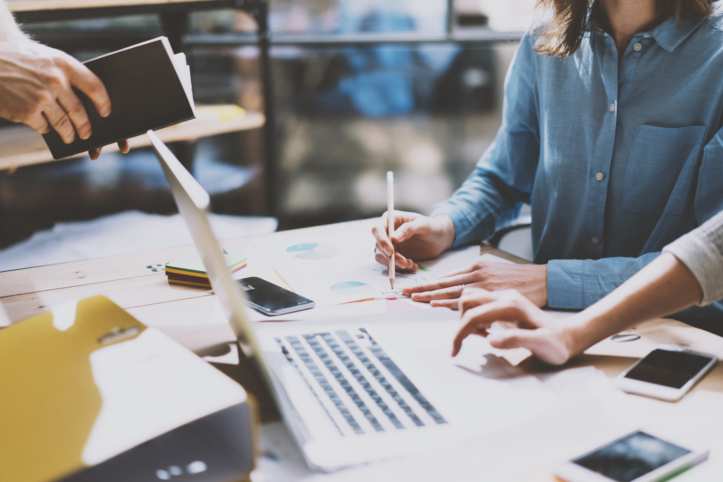 Team collaborating around a desk with charts, laptops, and documents, analyzing workplace data related to push and pull factors affecting employee retention.
